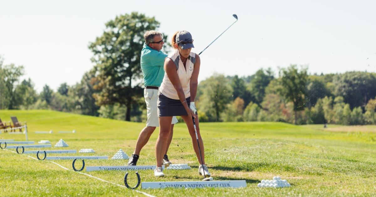 woman preparing to swing a golf club at a driving range