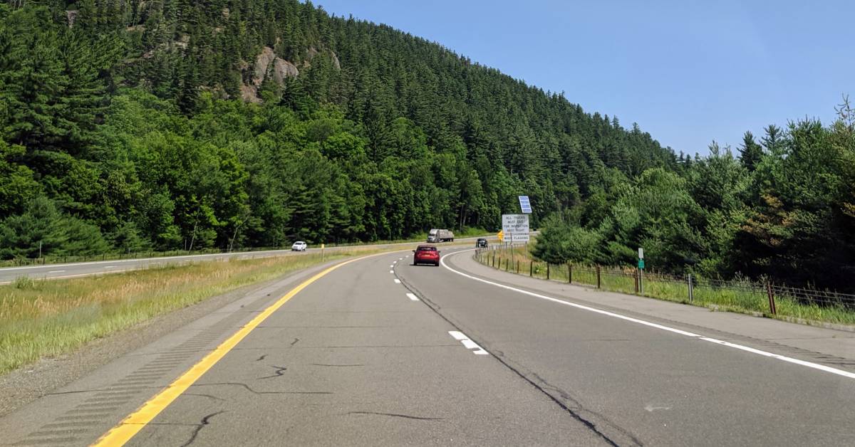 road with cars in the adirondacks near lake placid