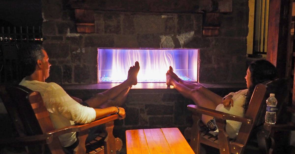 couple putting their feet up by outdoor fireplace
