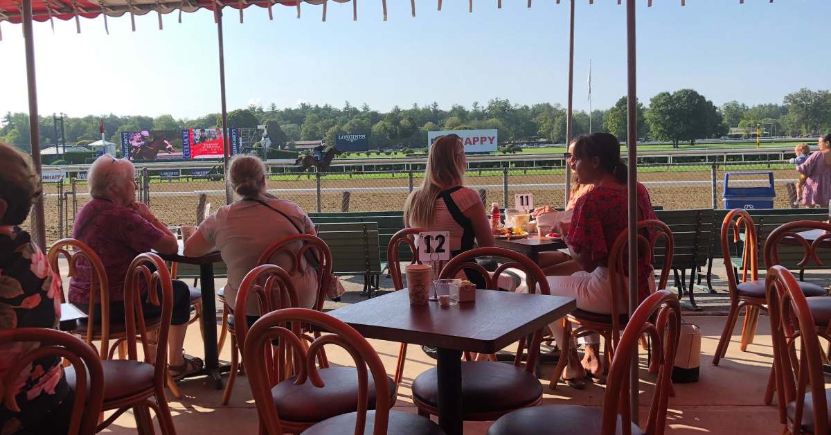 people dining at tables facing horse race track