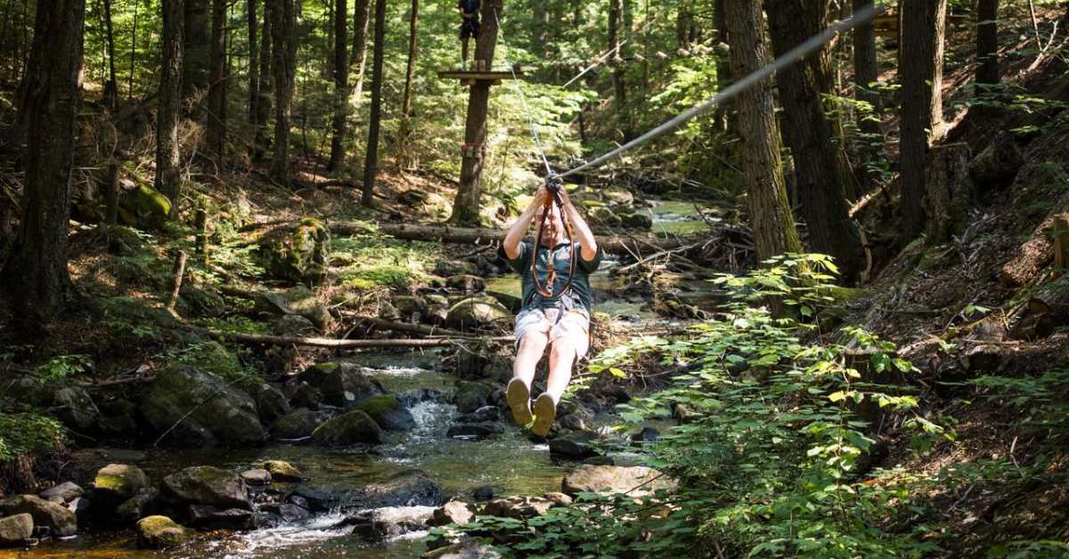 man ziplining in woods