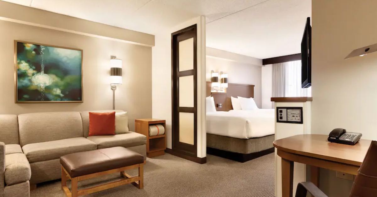 hotel suite with a bed and corner sofa in the living area