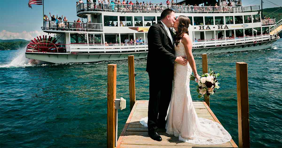 A couple kisses on a dock at the Inn at Erlowest, with a steamboat in the background.