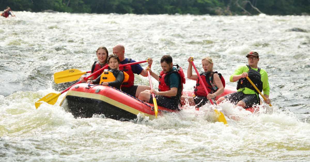 group of people whitewater rafting in red raft
