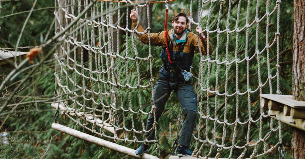 man on rope net on obstacle course