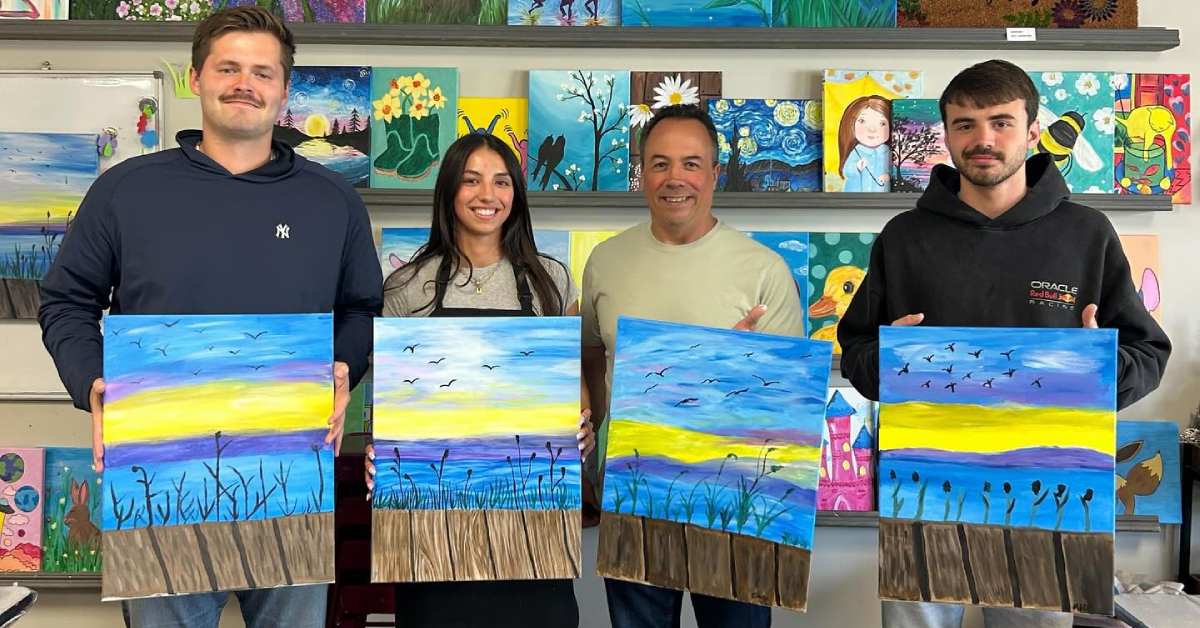 four people holding paintings