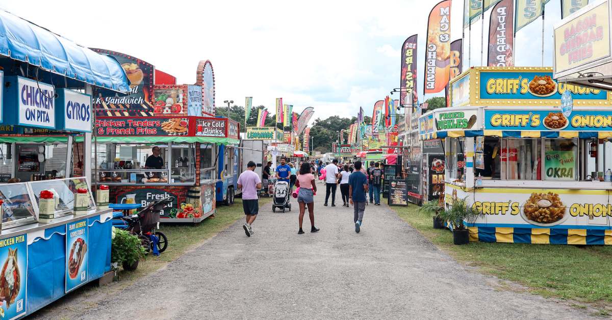 people walking around a county fair and food booths