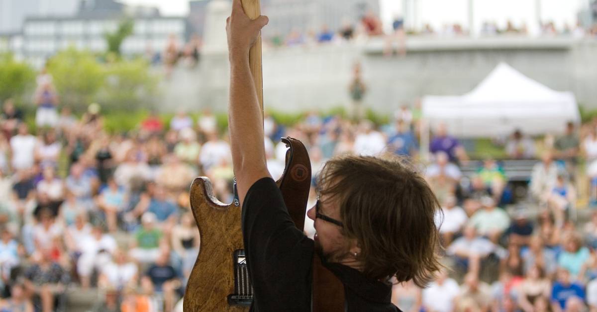 man with guitar on stage in front of crowd at albany dad fest