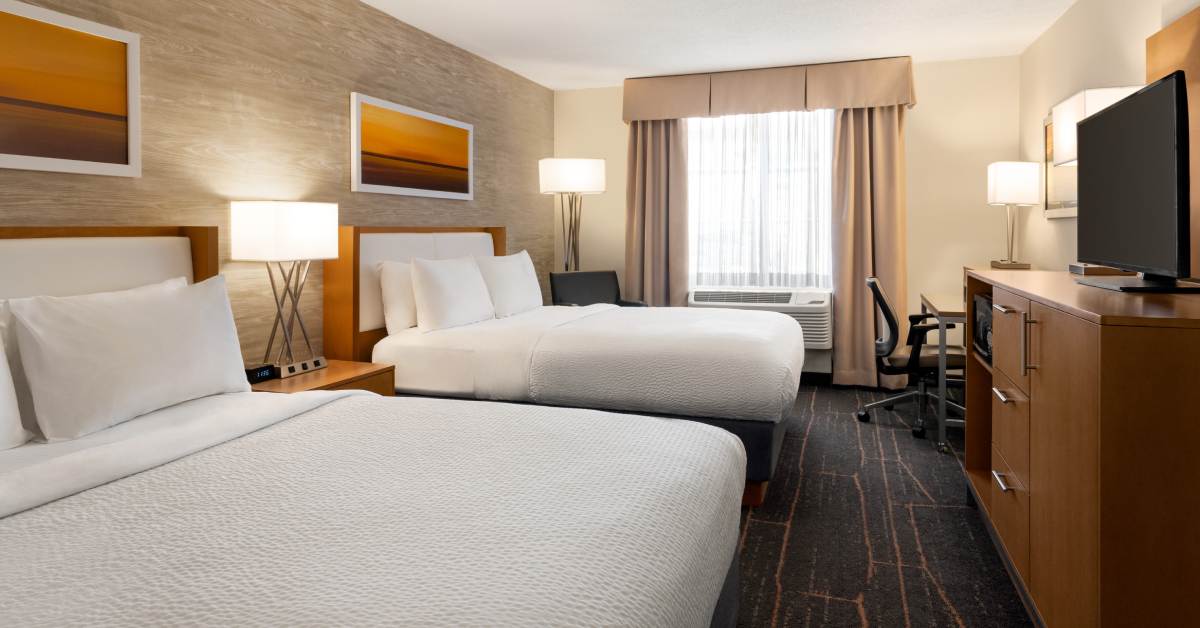 two beds in a hotel room with a TV and several lamps