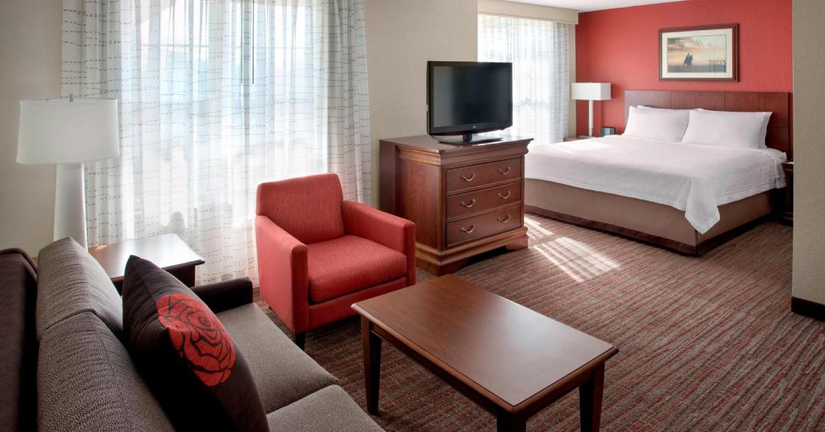 hotel suite with a bed, tv, table, and sofa