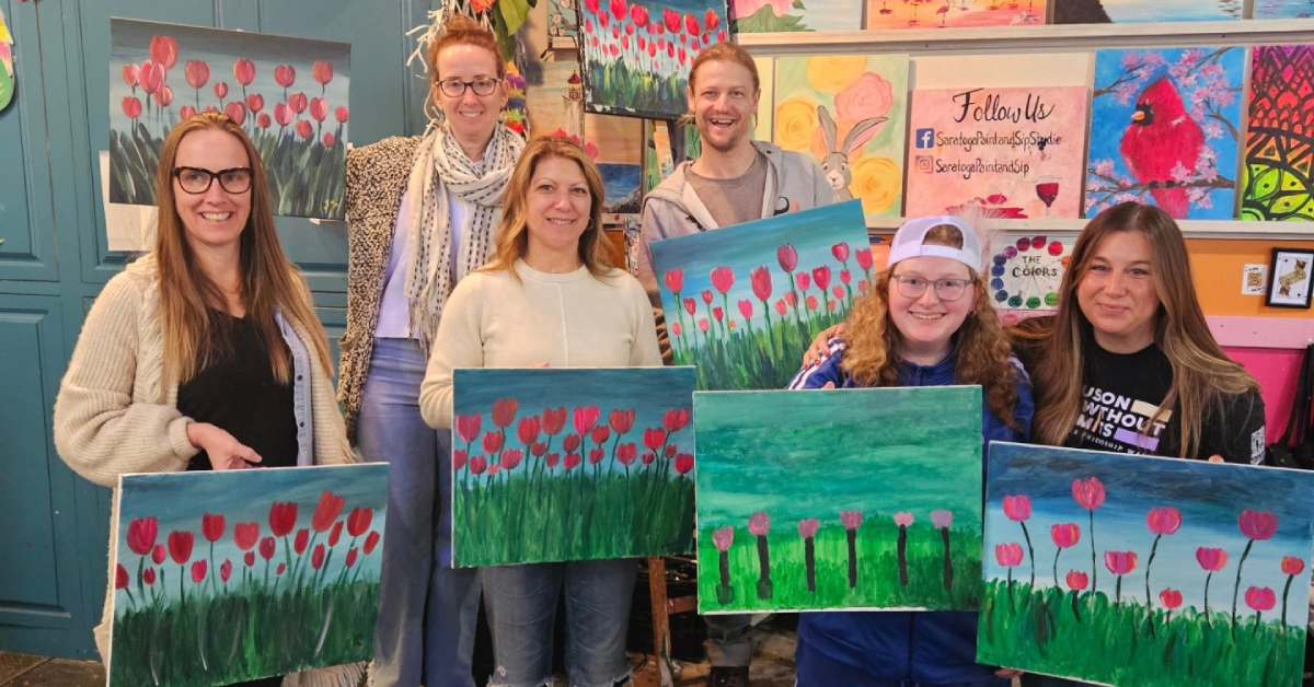 six people holding up paintings