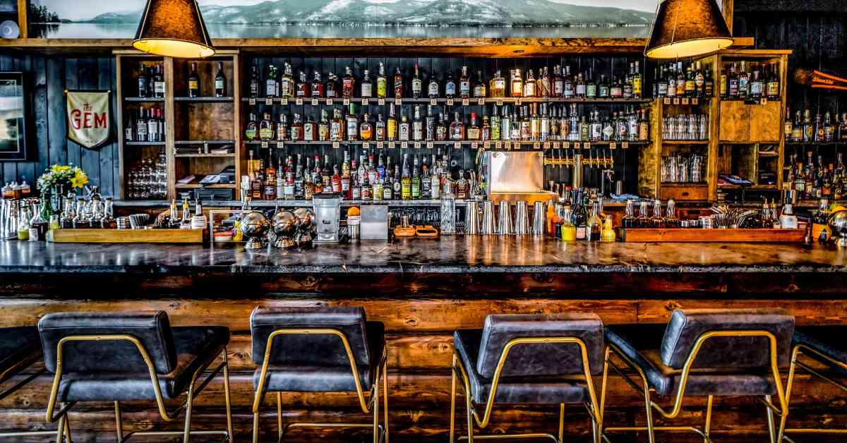 a rustic bar with a lot of bottles behind on the wall