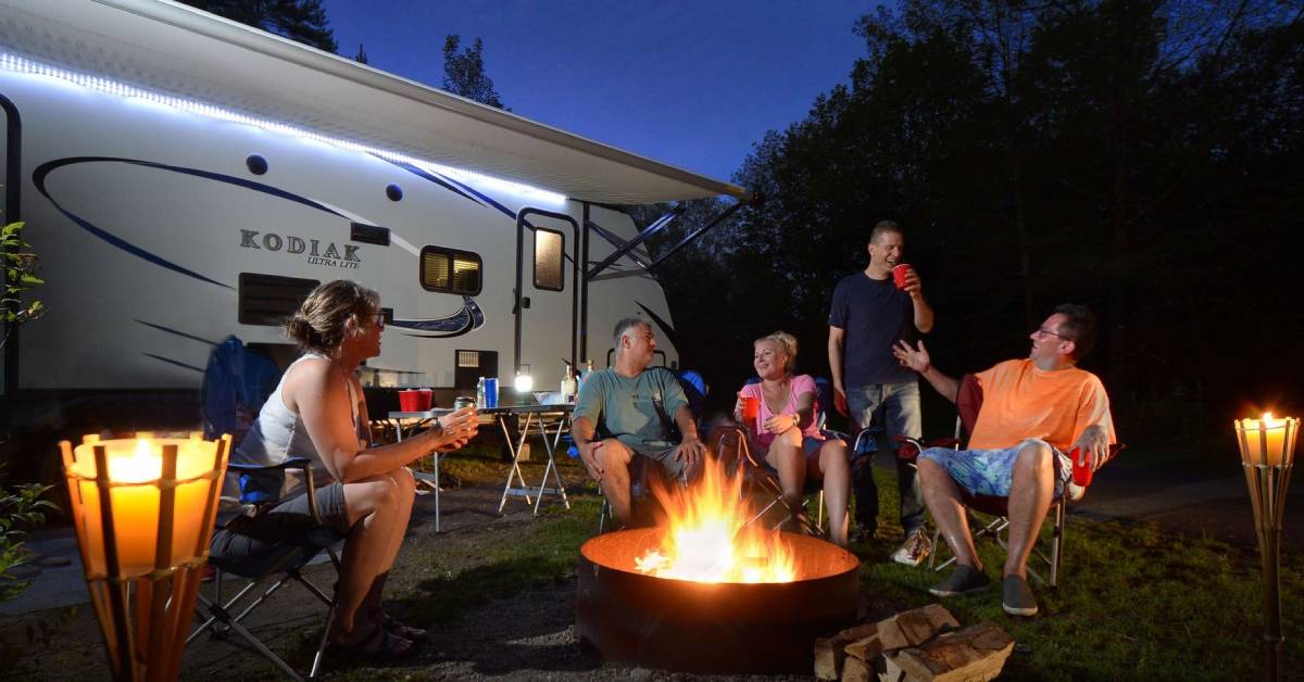 people around a campfire near an rv