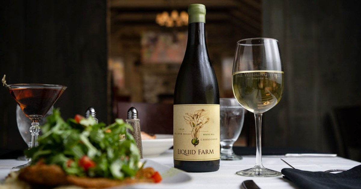 wine bottles, wine glass, and food on a table
