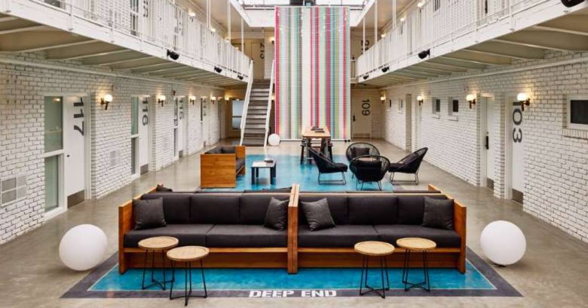 covered motel atrium with a bright blue rug, plus chairs and couches