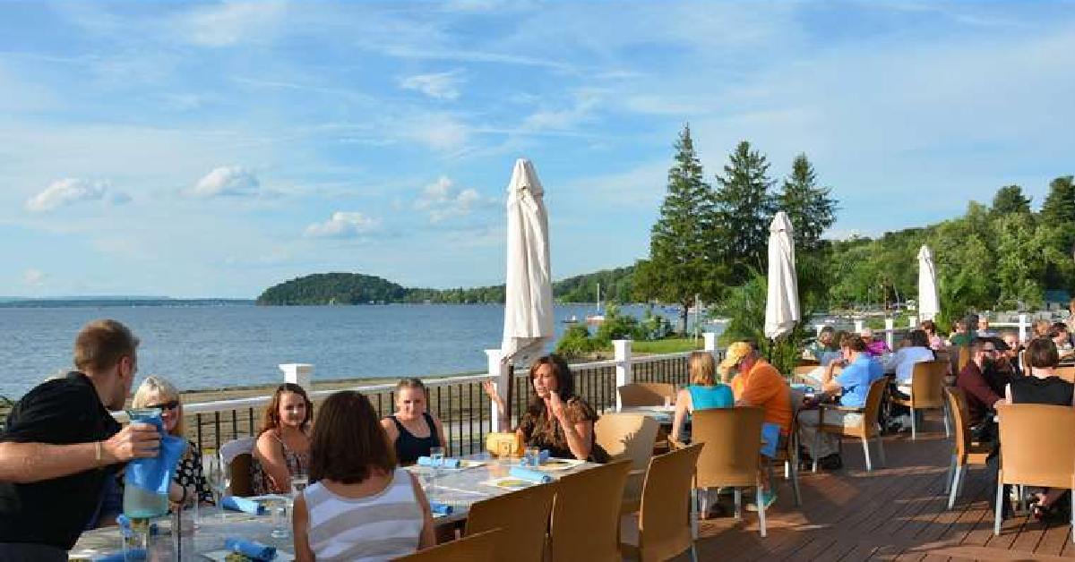 an expansive deck by the lake with people dining