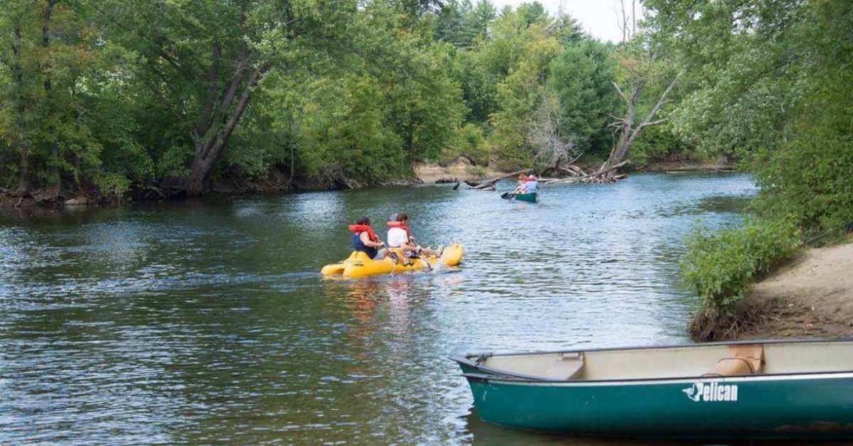 people heading down river in kayaks and canoe