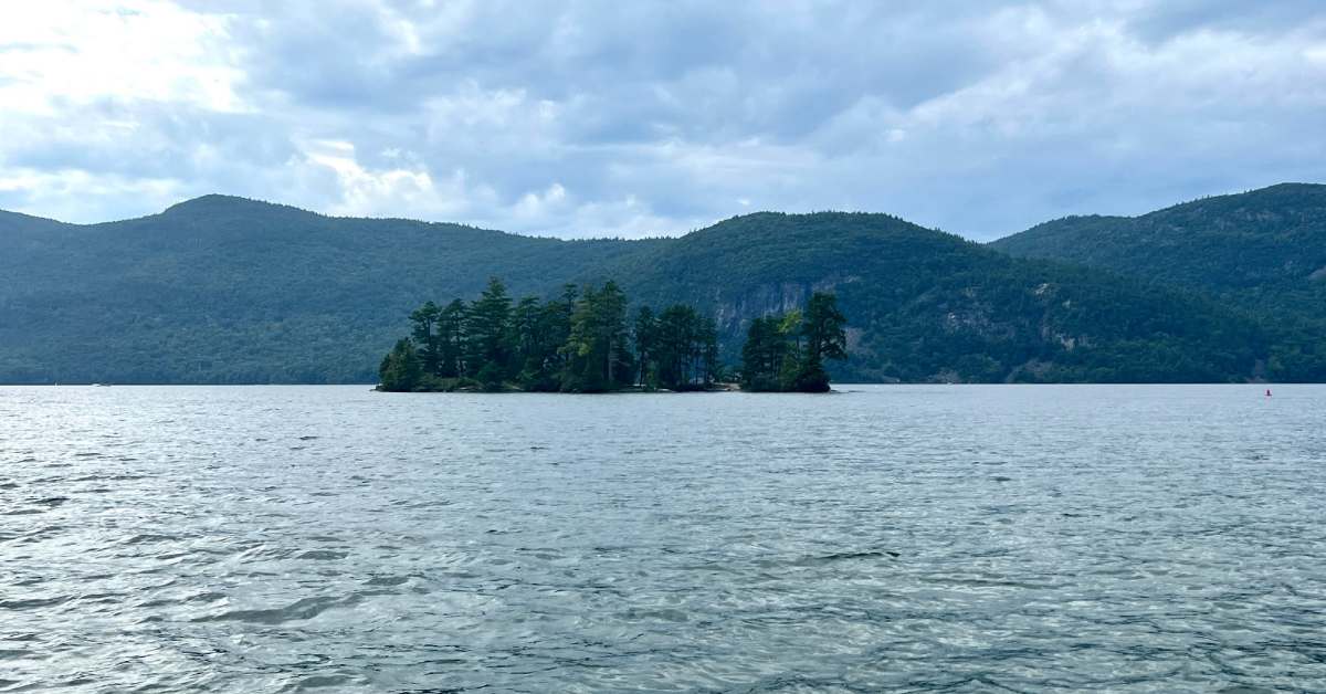 island on a lake with mountains behind it