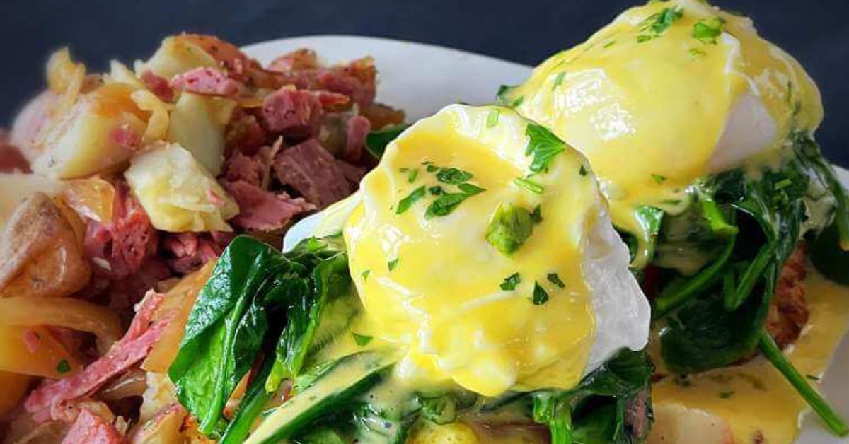 Eggs and greens with meat and potatoes on the side on a white plate