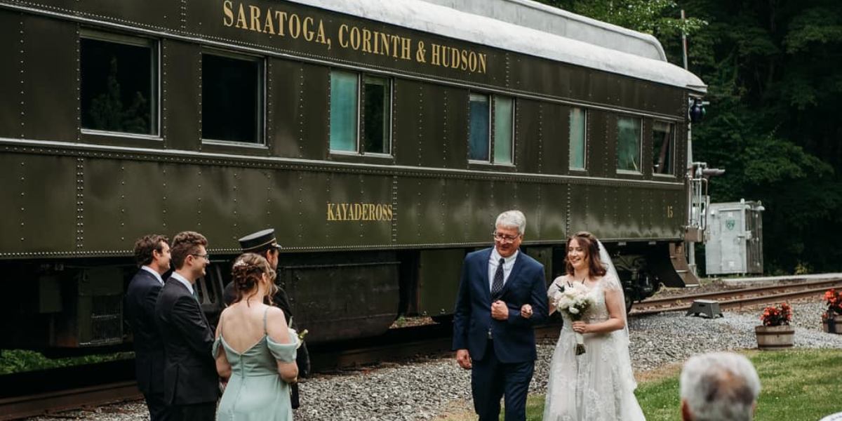 four people outside a train car preparing for a ceremony