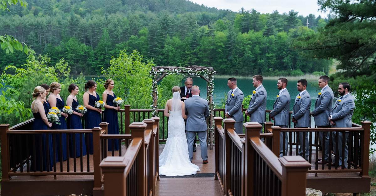 Bridal party and couple with a lake backdrop and greenery everywhere.