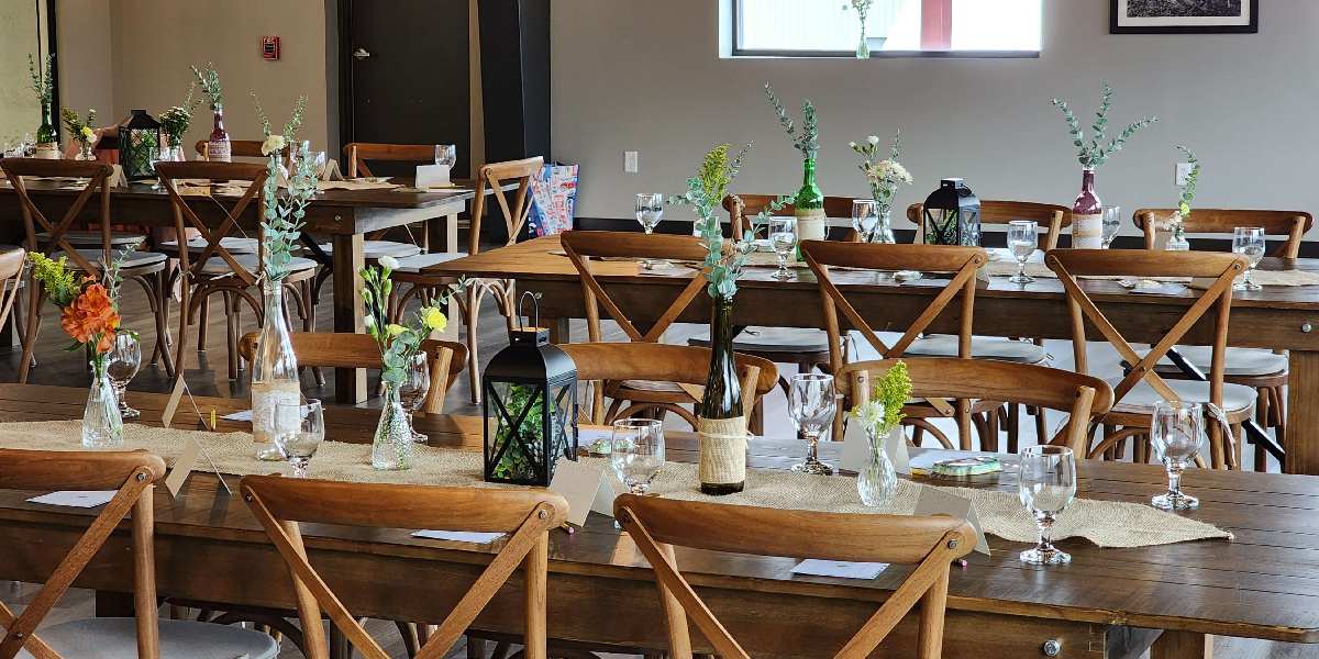 Long wooden rectangular tables with wine bottles on them