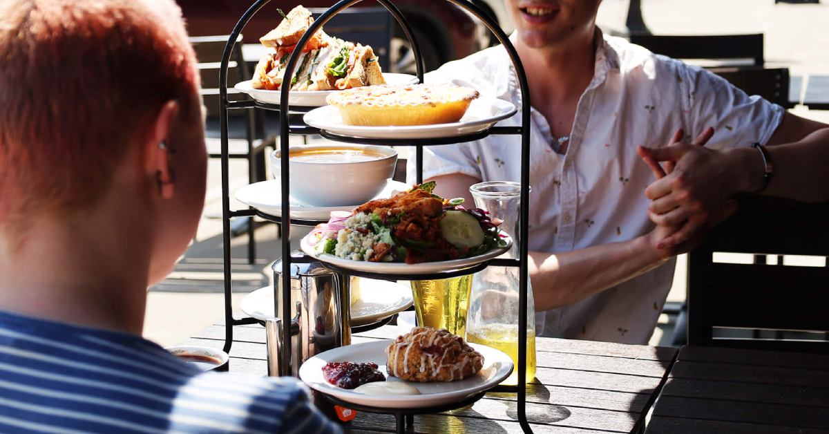Tower of three different brunch foods, person in the foreground and background