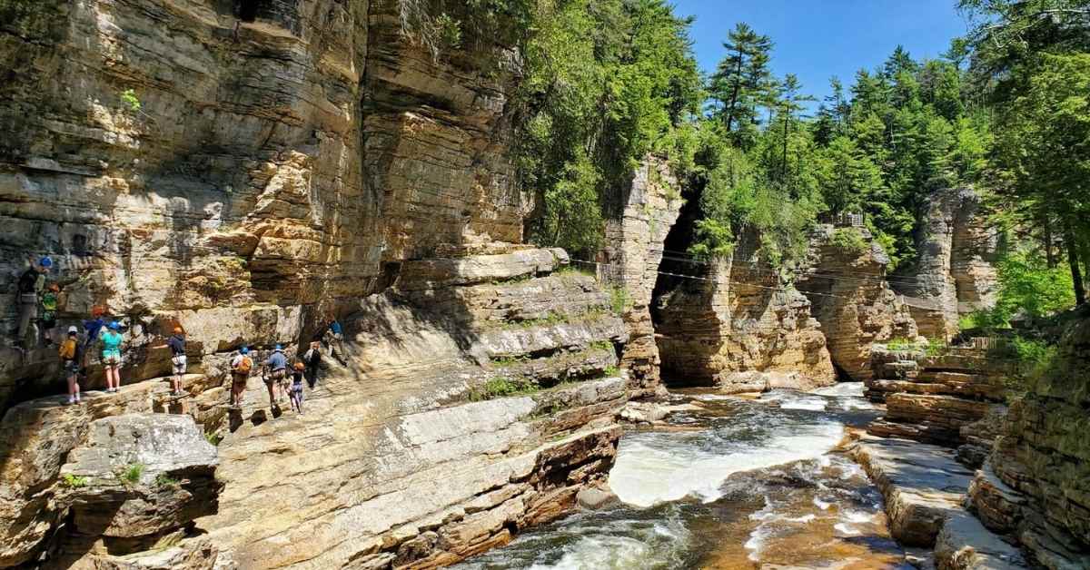 people climbing along rock cliffs above river