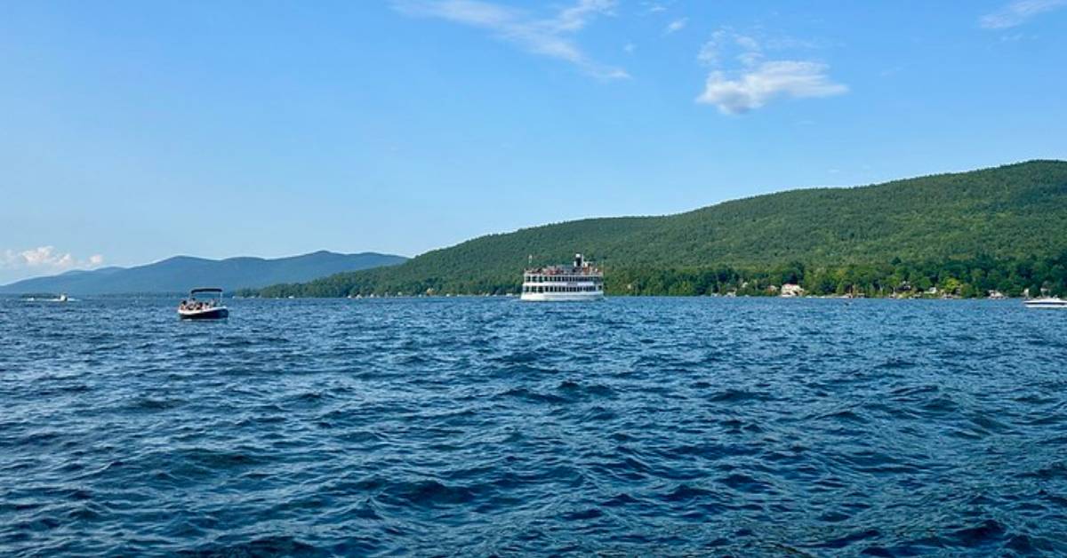 motorboats and steamboat on a lake with mountains nearby