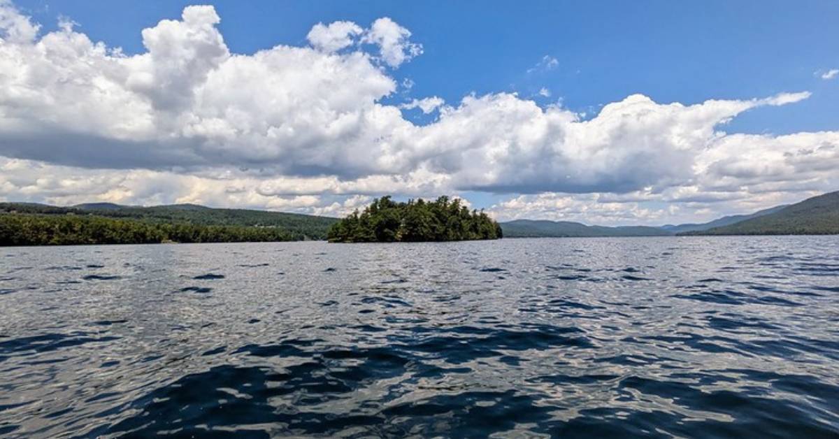an island on a lake with clouds on a blue sky day