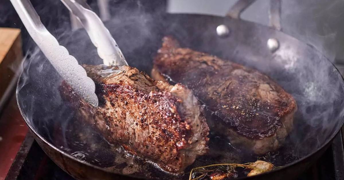 steak being turned over in skillet