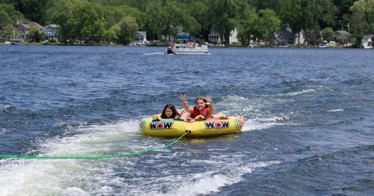 two girls in yellow tube being pulled by a boat