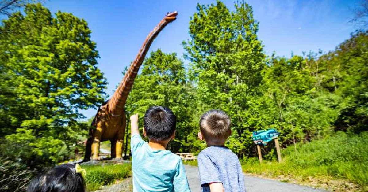 two boys looking up at a dinosaur