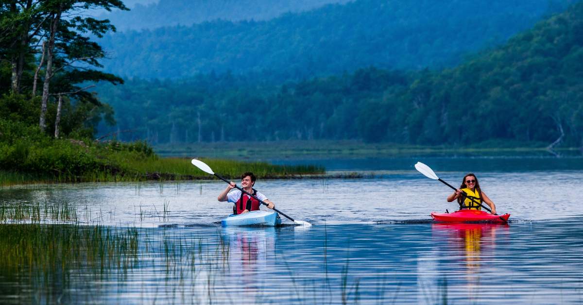 two kayakers on a scenic lake in the woods