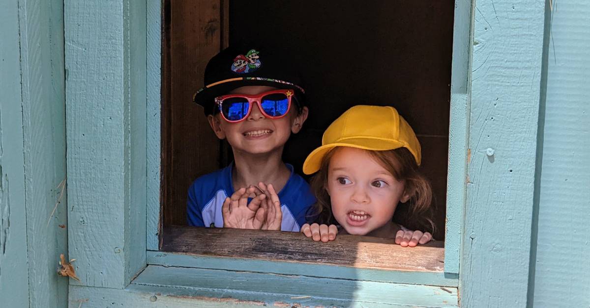 two little kids looking out window of great escape house