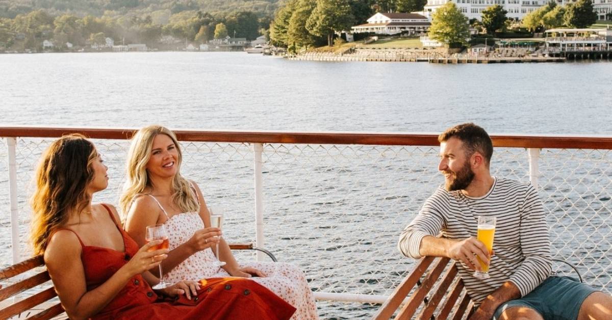 three people drinking cocktails on a boat on lake george