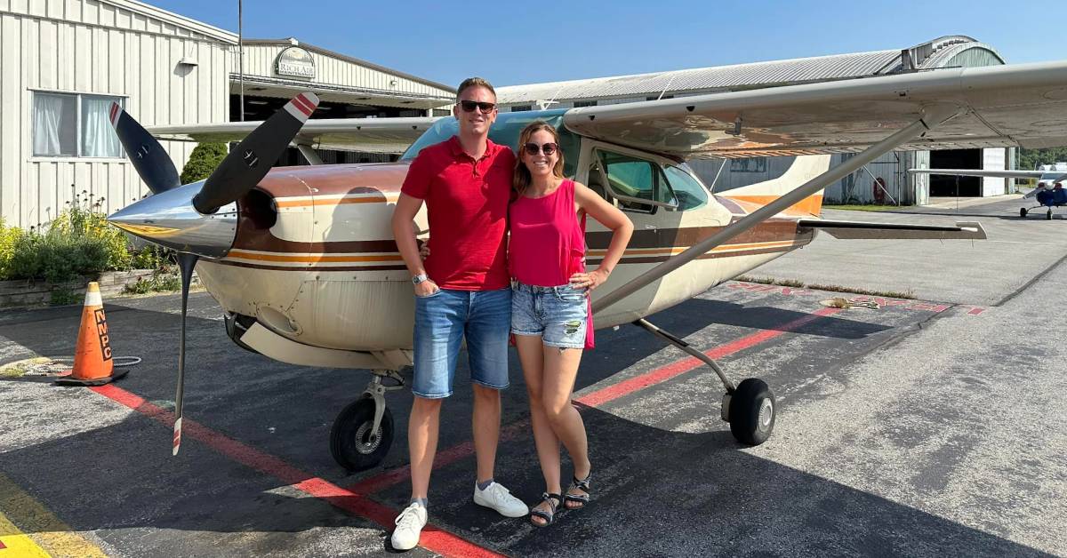 couple poses in front of small plane