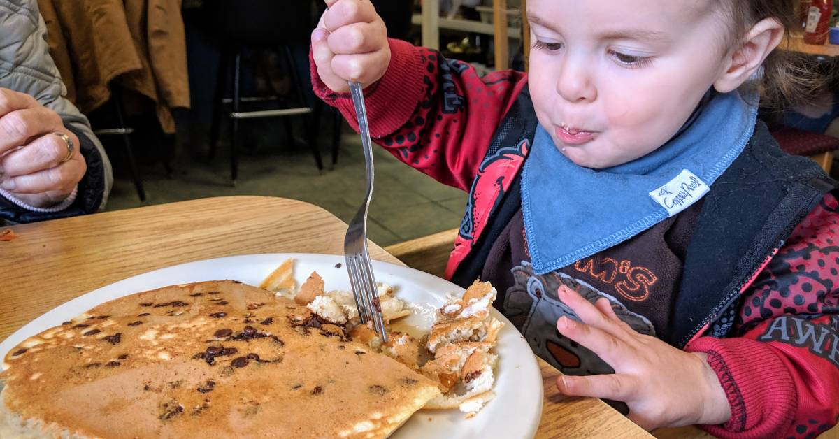 toddler eating chocolate chip pancakes