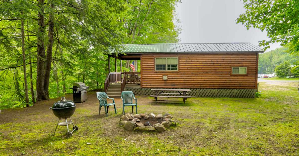 exterior of a rustic cabin with a fire pit and grill nearby
