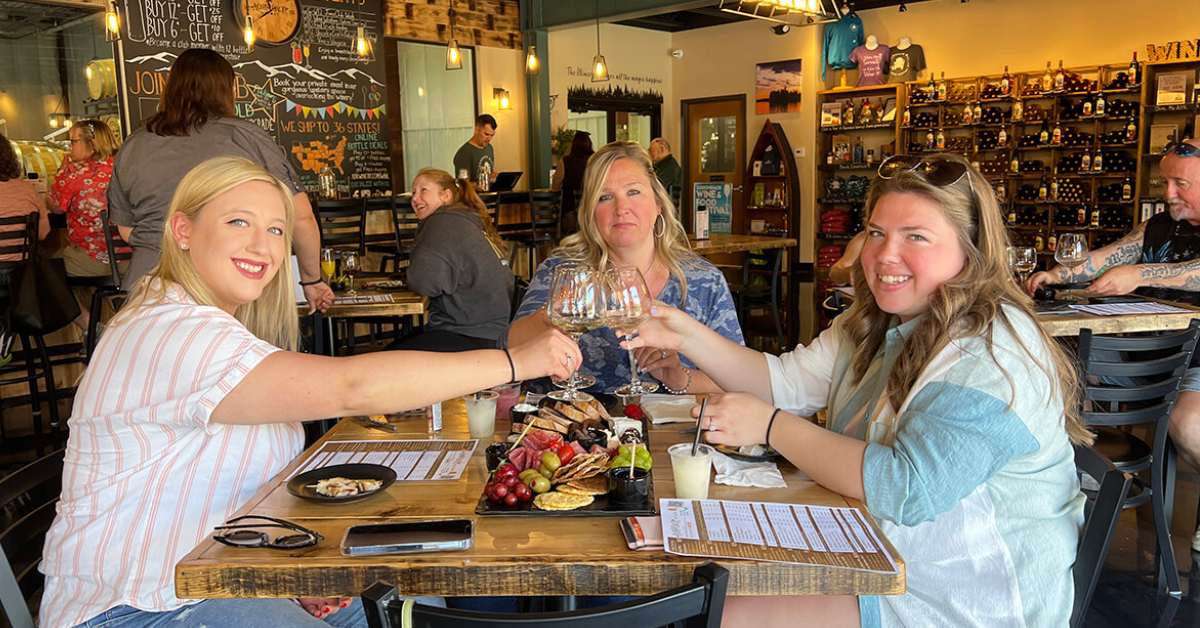 three women raising there glass over a charcuterie board
