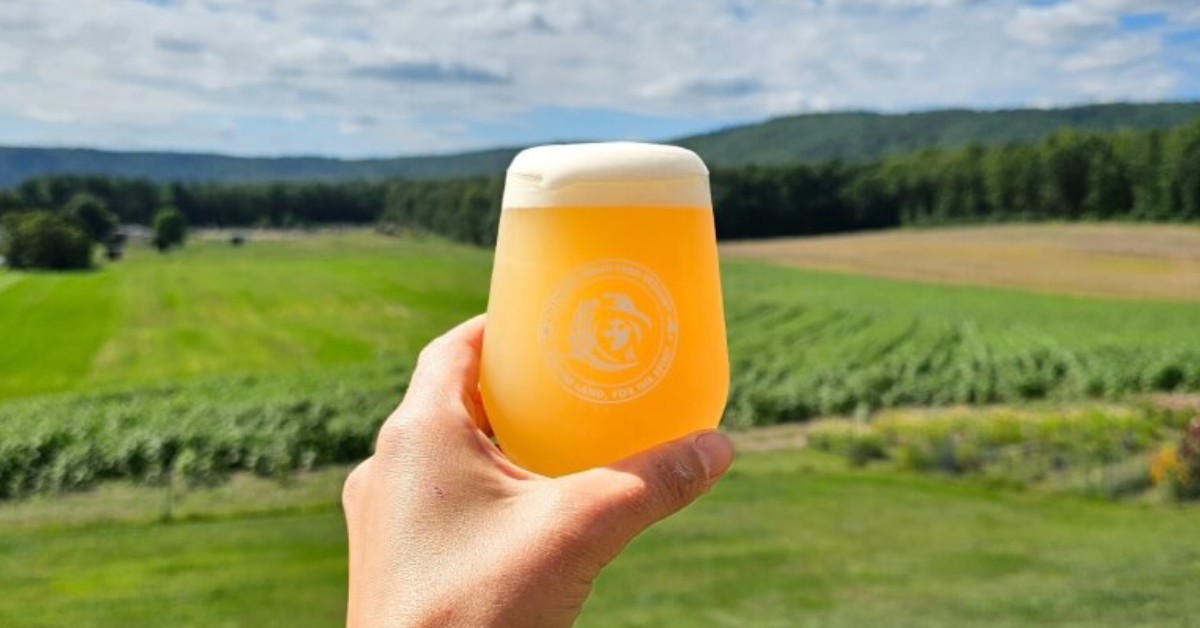 Hand holding glass of beer with mountain backdrop
