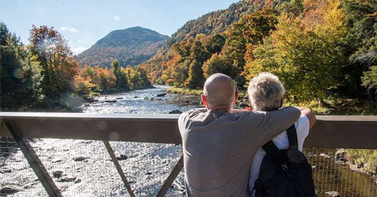 Couple enjoying the fall foliage and water on a bridge
