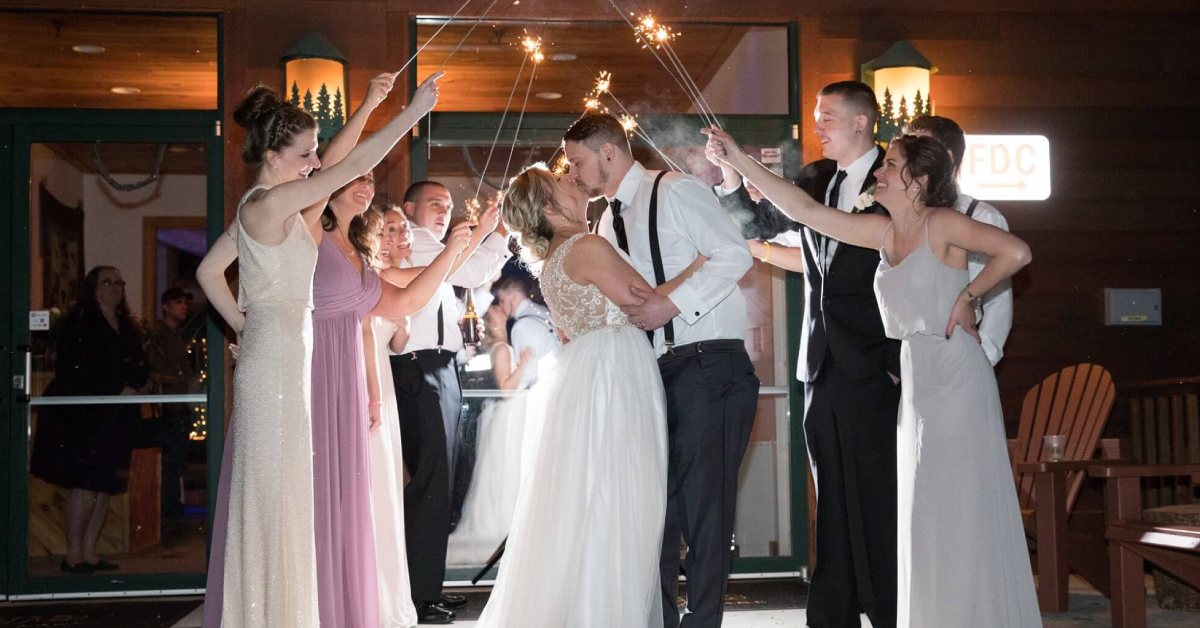 Couple kissing underneath sparklers people are holding