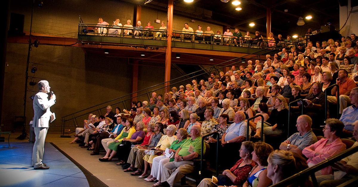 Audience in a crowded auditorium watching a man on a mic