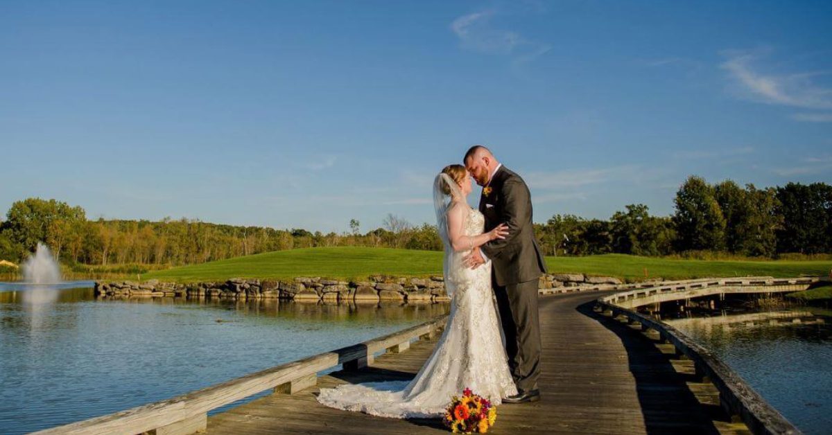 bride and groom on a bridge with a golf course in background