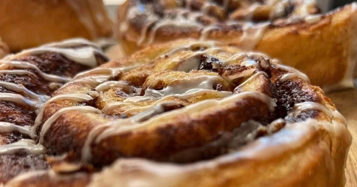 Top of a cinnamon bun with icing drizzled and more in the background