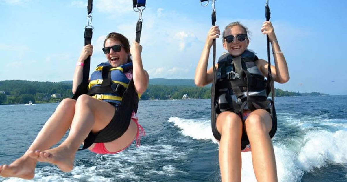 two women parasailing above a lake