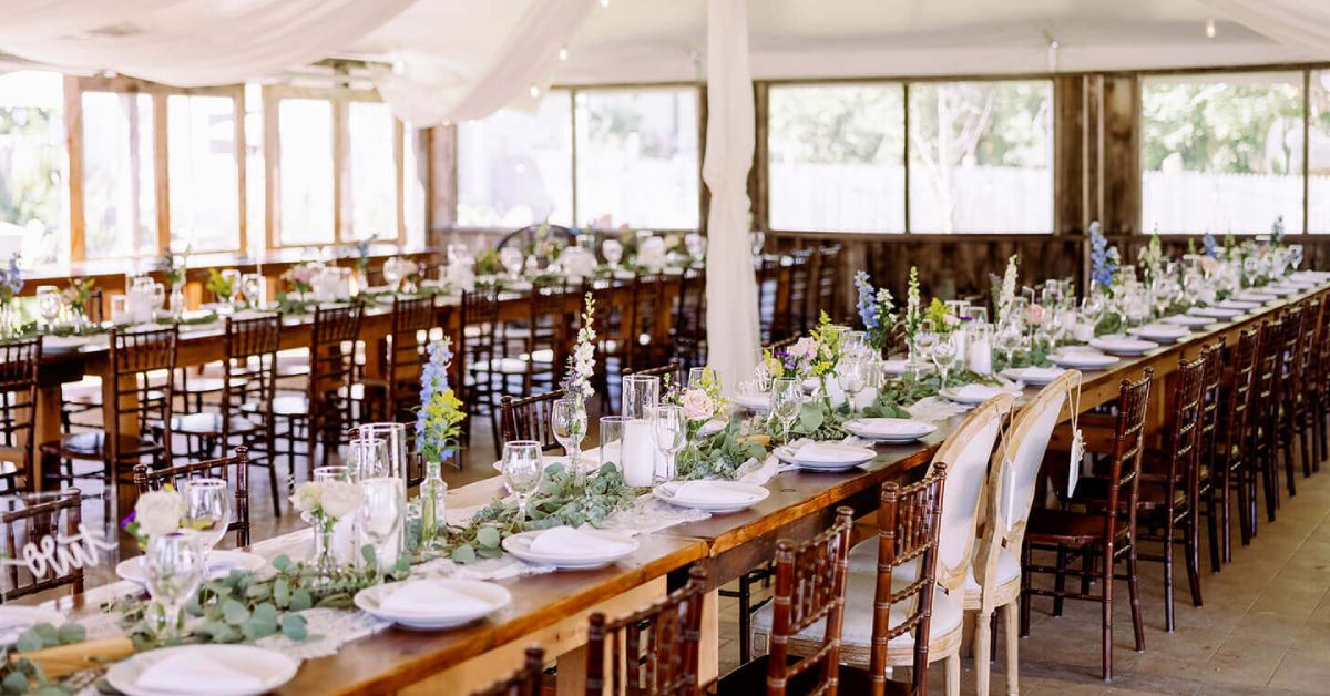 Long wooden tables with wooden chairs with all glassware and centerpieces throughout