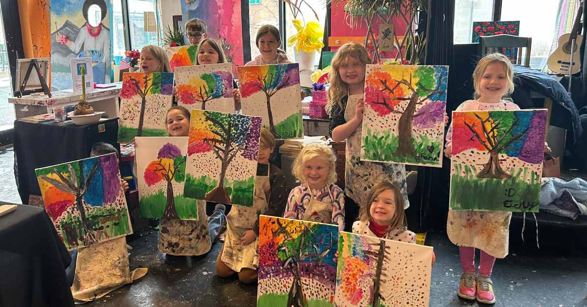 kids holding up paintings of a colorful tree