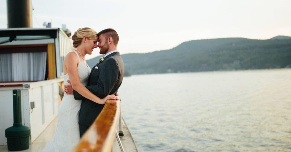 Couple with their foreheads against one another on a steamboat with a lake backdrop